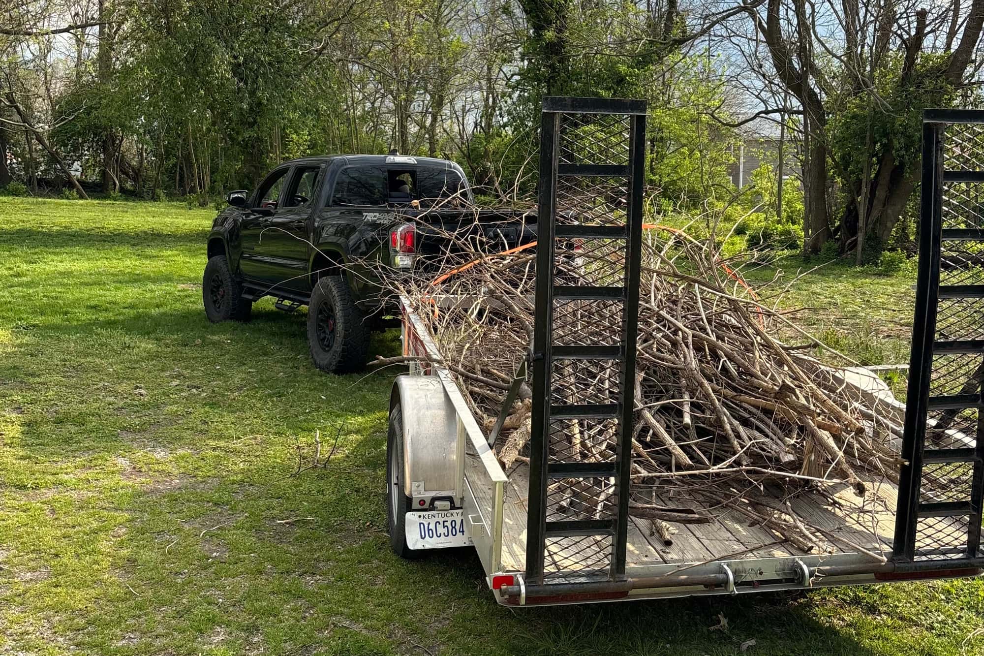 A pickup truck and utility trailer loaded with brush and cut limbs