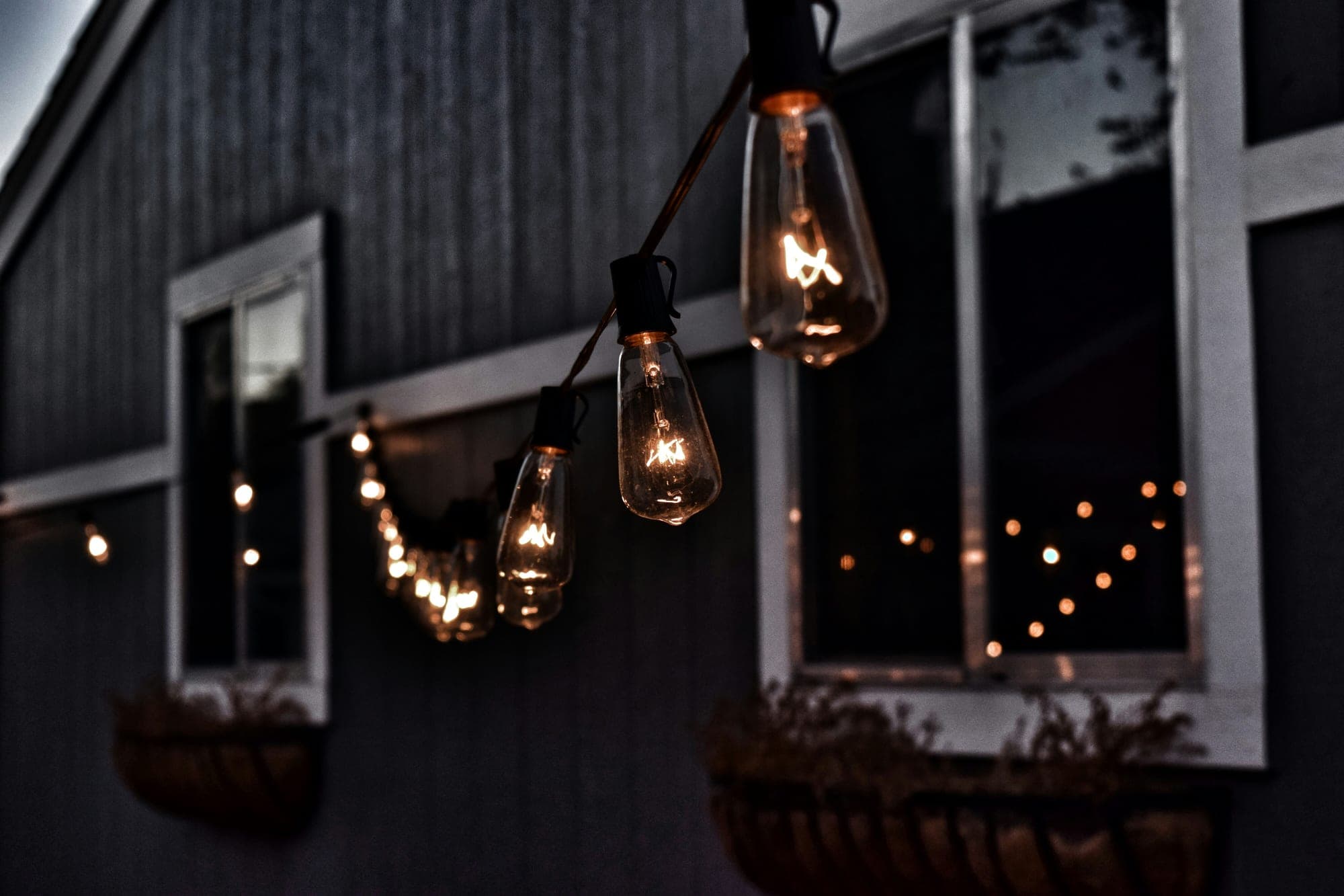 Warm string lights hung along the outside of a building at dusk